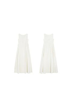 A flat lay of a cream sleeveless A-line floor-length dress with side pleats and a round neckline.
