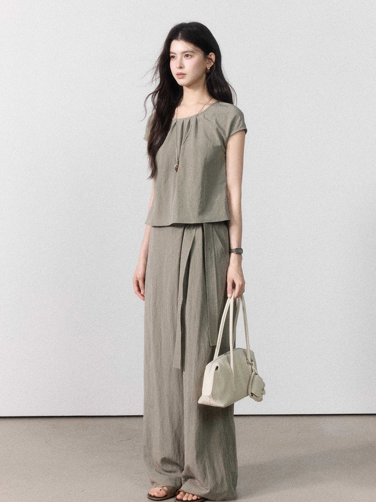 Taupe grey wide-leg pants with a straight hem, visible from the back.