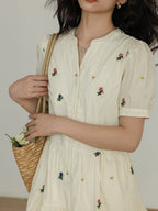 Front button placket on a cream dress with embroidered flowers.