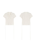 A cream polka dot short-sleeve top with a V-neck and button-front closure shown in flat lay.