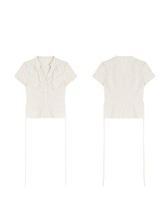A cream polka dot short-sleeve top with a V-neck and button-front closure shown in flat lay.