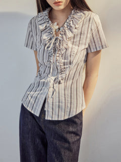 Ruffled trim and button placket on a grey purple striped blouse.