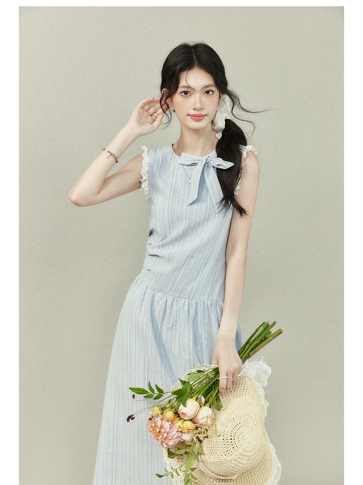 Light blue dress with vertical stripes, lace trim on the shoulders and hem, a bow tie neckline, gathered waist, A-line silhouette, and lace trim.