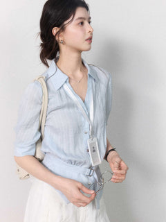 Light blue blouse with a collar, three-quarter sleeves, and gathered waist.