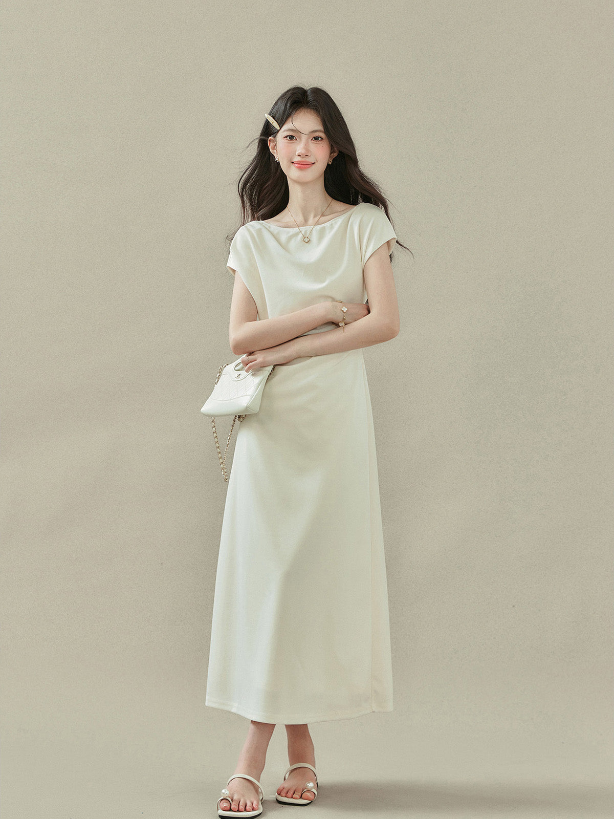 Cream off-shoulder dress featuring draped fabric at neckline and waist, side slit.