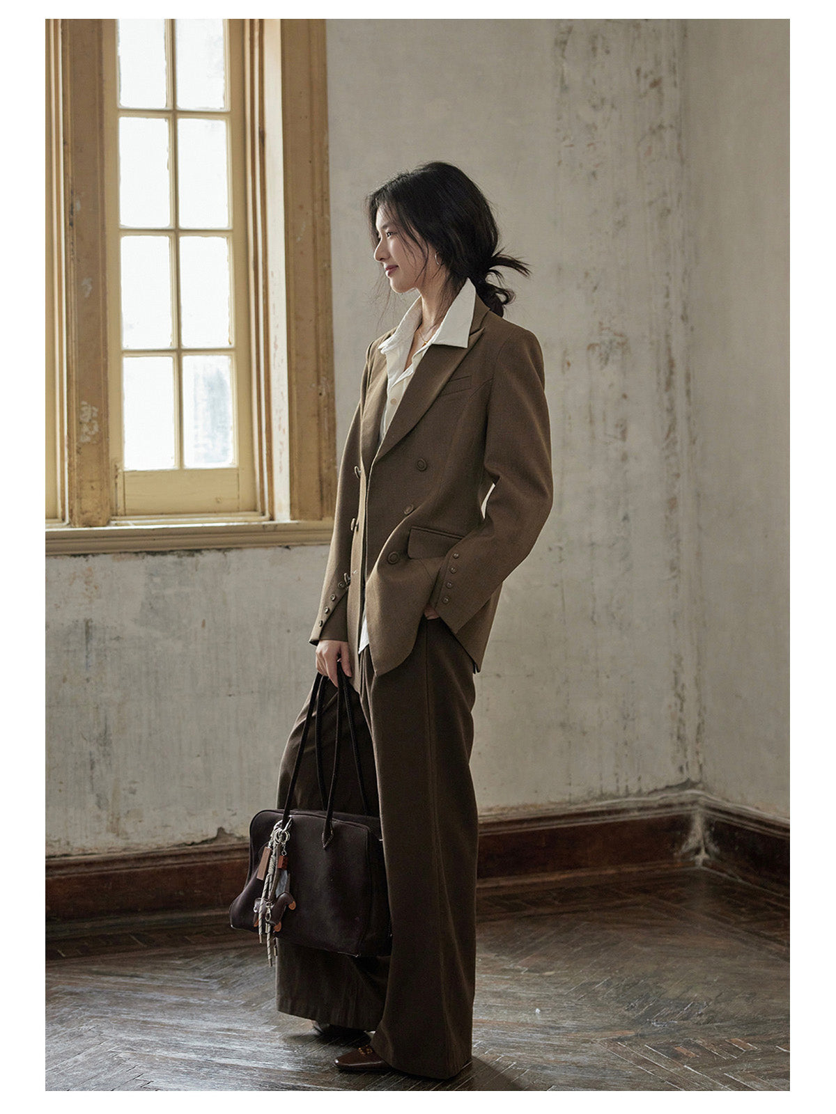 Side profile of brown blazer showing relaxed silhouette and buttoned cuffs.