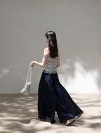 Blue floral camisole worn with dark pants and woven bag