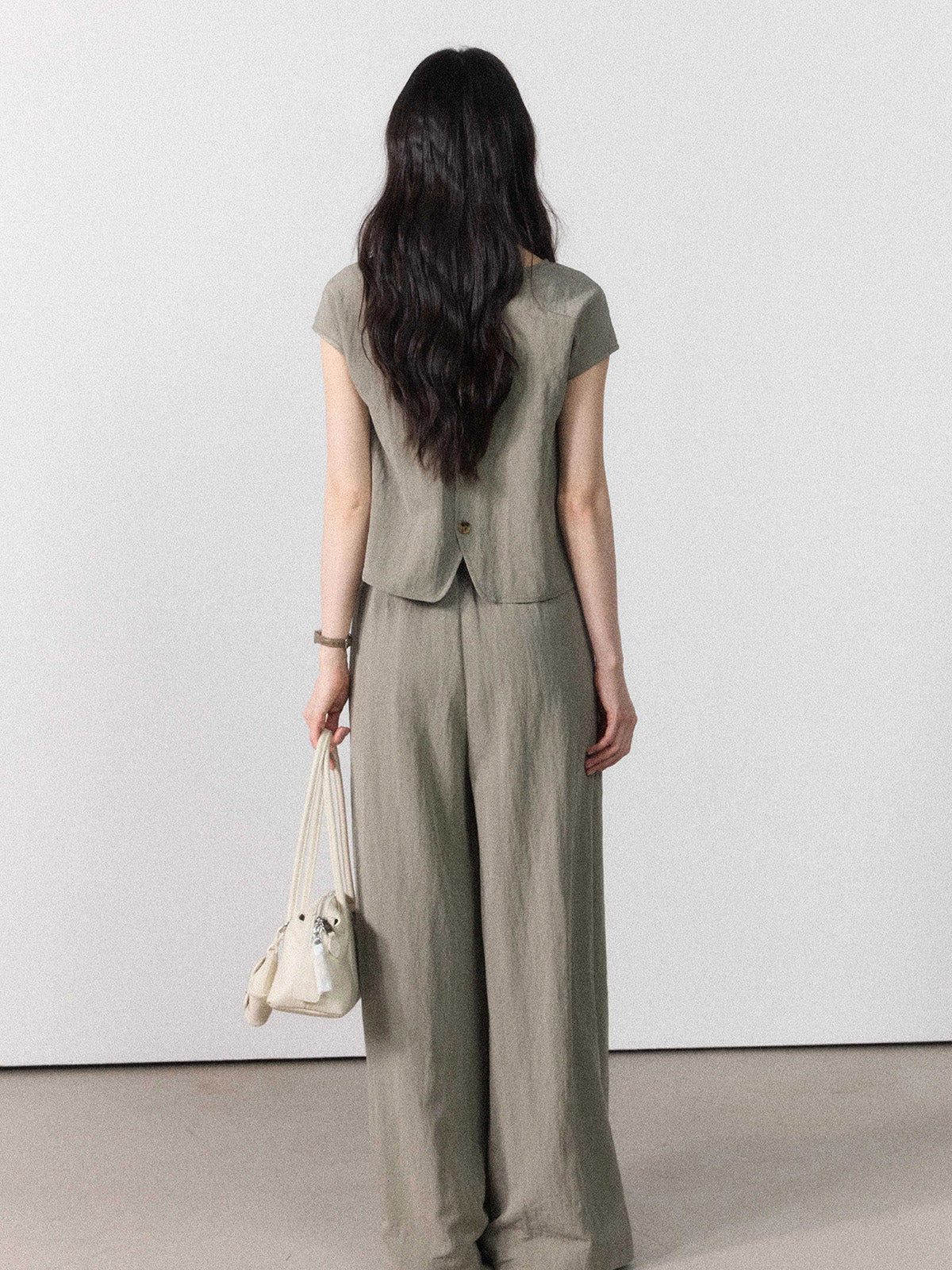 Back view of taupe grey wide-leg pants showing the tie belt and straight hem.