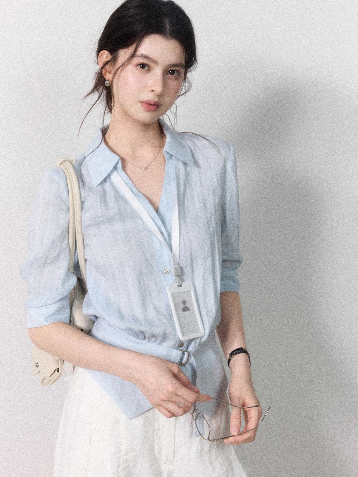 Button-closure light blue blouse with a tied belt at the waist.