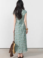 A woman in a long, light blue dress with a green leaf pattern viewed from the back.