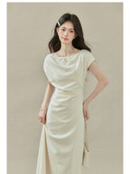 Close-up of cream off-shoulder dress with short sleeves and draped neckline.