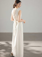 A woman in a white A-line dress with a button placket and tie belt, viewed from the back.