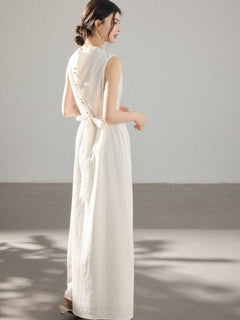 A woman in a white A-line dress with a button placket and tie belt, viewed from the back.