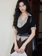 A woman in a black and white striped layered V-neck top with short sleeves, looking at the camera.