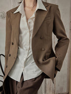 Close-up of brown double-breasted blazer with notched lapels and buttoned cuffs.