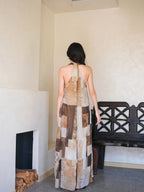 A woman seen from the back, wearing a long dress with a brown and beige patchwork pattern.