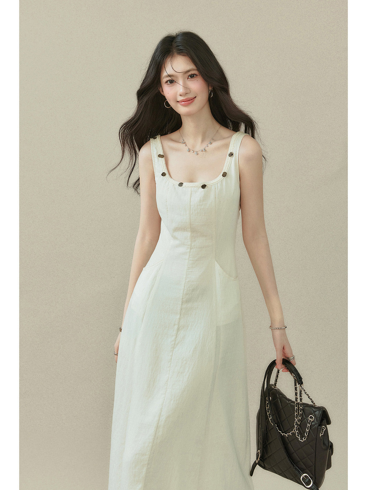 Ivory sleeveless dress with a straight hem, side pockets, and button details on the neckline.