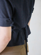 A close-up of the back of a navy striped fitted top showing a peplum hem and side ties.
