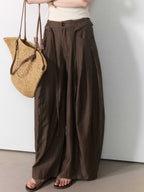 Brown wide-leg pants shown from the side, highlighting pleats and a straight hem